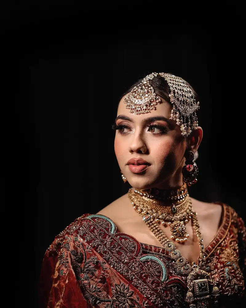 A bride in full jewellery photographed against a black background.